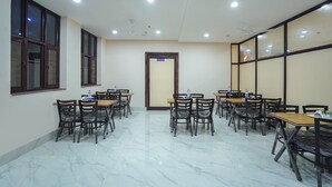 A conference room with multiple tables and chairs, a ceiling fan, and a door labeled "KITCHEN". - Fabhotel Hc Mohali Inn (Mohali)