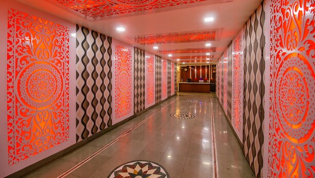 Un couloir agrémenté de panneaux muraux décoratifs et d’un sol à motifs, qui mène à un espace d’accueil.