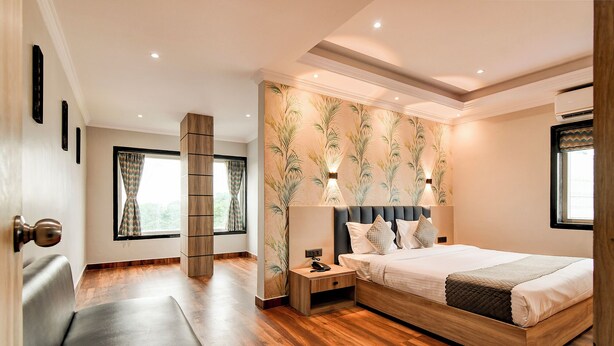 Un dormitorio moderno con una cama de madera, una mesita de noche, un banco y un ventanal con cortinas.