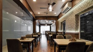 Interior de un restaurante con suelo de madera, sillas de tonos oscuros y mesas.