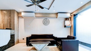 Una sala de estar moderna con un sofá, una mesa de centro, un ventilador de techo y un reloj fijado a la pared.