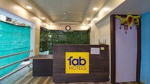 Et receptionsområde med et skilt fra 'fab hotels', en receptionsdisk, et ur og en dekorativ guirlande.