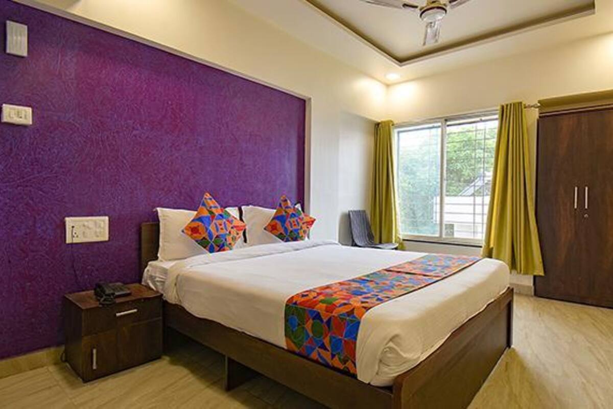 A bedroom with a bed, a nightstand, a wardrobe, and a window with curtains.