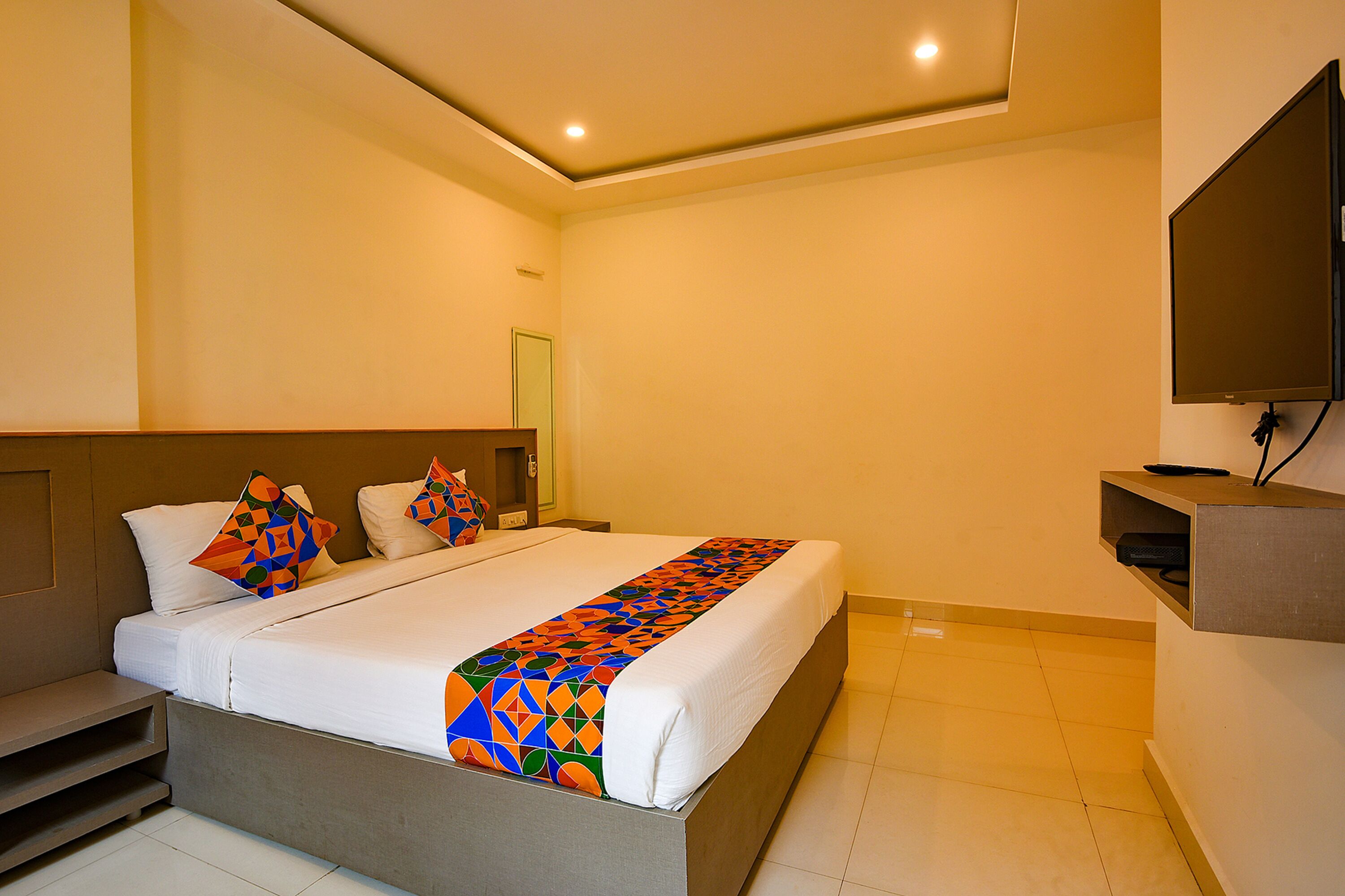 A hotel room with a bed, a TV, and a desk.