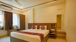 Habitación de hotel con una cama grande, un armario, una mesita de noche con teléfono y un espejo.