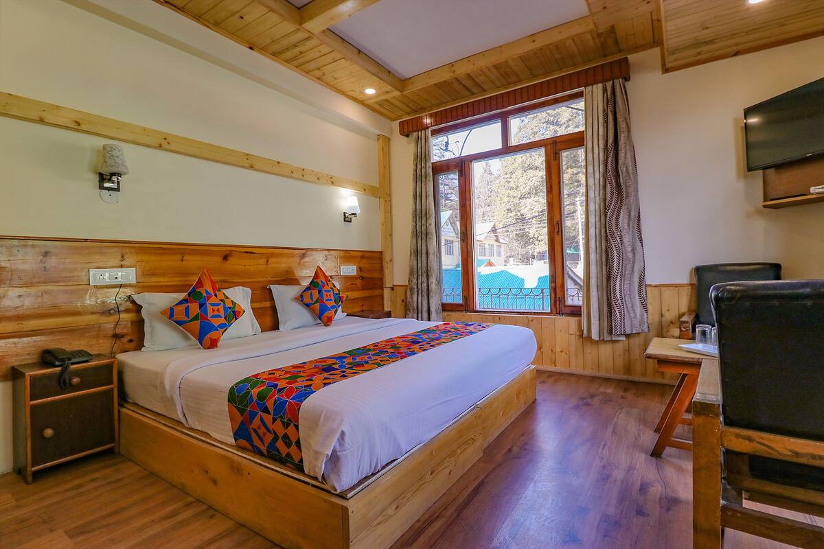 A wooden-paneled bedroom with a bed, bedside table, and a TV mounted on the wall.