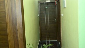 A narrow hallway with a wooden door marked "302" and a potted plant at the end. - Fabhotel Golden Bliss (Bhubaneshwar)
