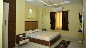 A bedroom with a bed, a nightstand, a wardrobe, an air conditioning unit, and a ceiling fan. - Fabhotel Golden Bliss (Bhubaneshwar)