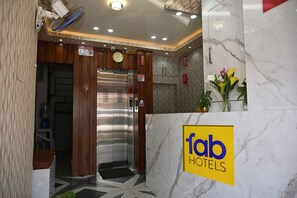 A hotel reception area with a marble counter, a clock, and an elevator. - Fabhotel Golden Bliss (Bhubaneshwar)