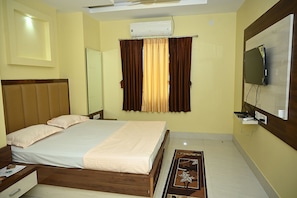 A hotel room with a bed, a television mounted on the wall, an air conditioning unit, and a window with curtains. - Fabhotel Golden Bliss (Bhubaneshwar)