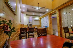 A dining area with wooden walls, a ceiling fan, and a table with chairs. - Fabhotel Gaba Corporate Suites (Noida)