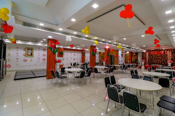 Un amplio comedor interior con varias mesas y sillas, decorado con globos y arreglos florales.
