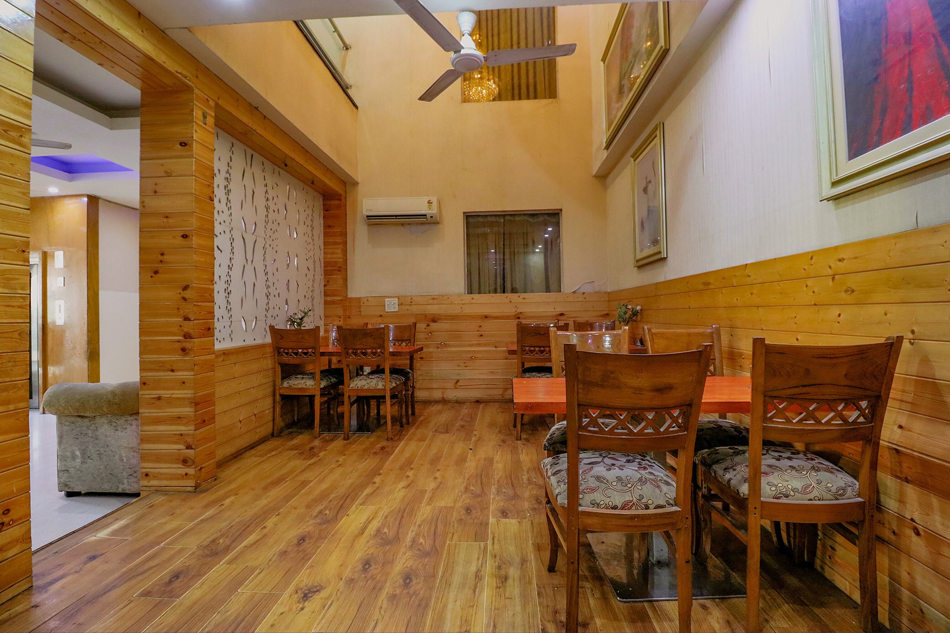 Interior de madera con zona de comedor, ventilador de techo y equipo de aire acondicionado.