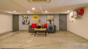 Un vestíbulo con dos personas sentadas en un sofá, una mesa de centro y un letrero que dice 'Fab Hotels'.