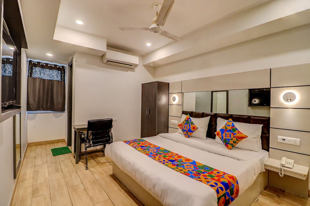 Habitación de hotel con una cama grande, un escritorio, un armario, un espejo y un ventilador de techo.