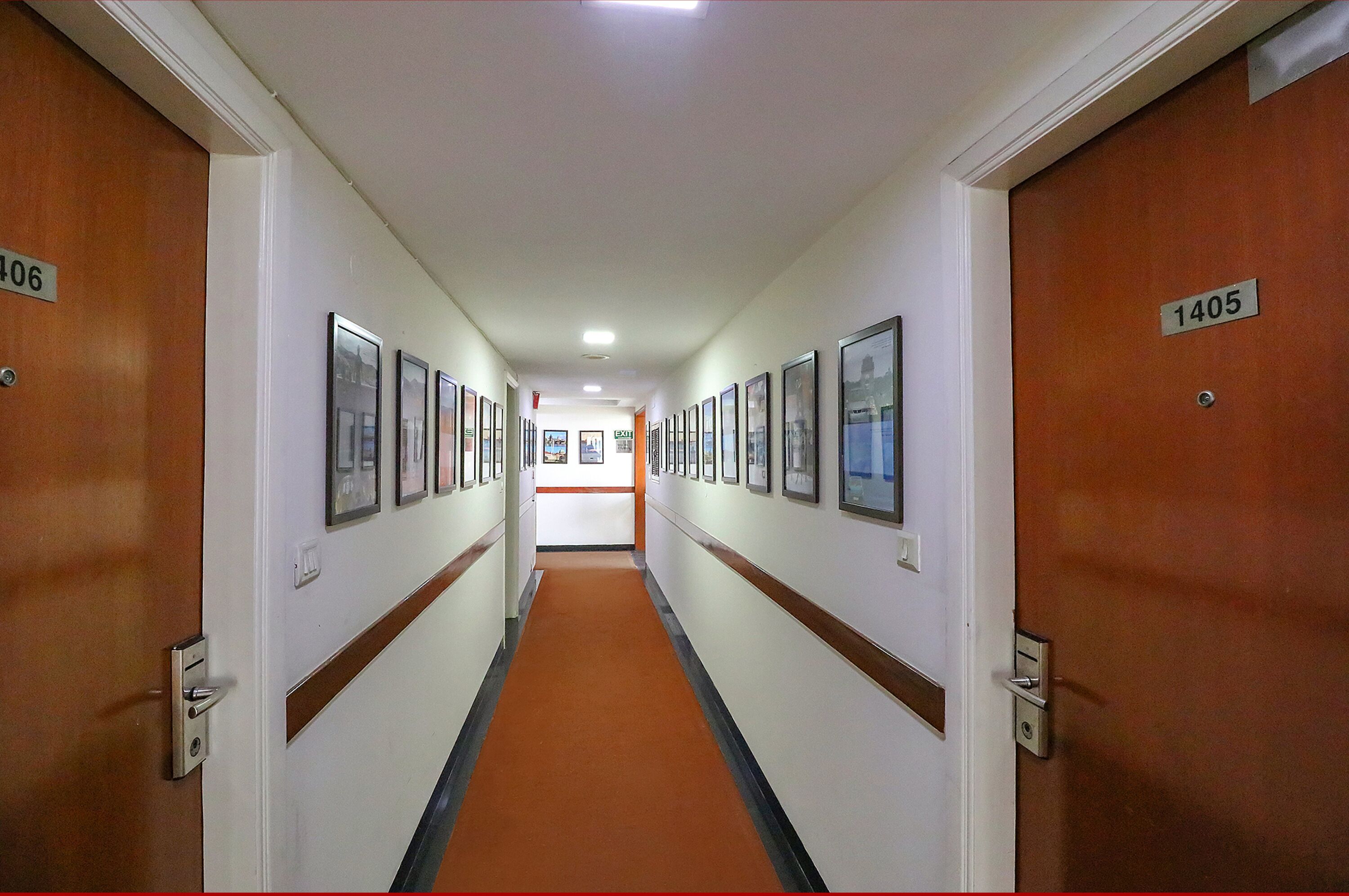 A hotel hallway with doors numbered 1405 and 1406, featuring framed pictures on the walls and a carpeted floor.