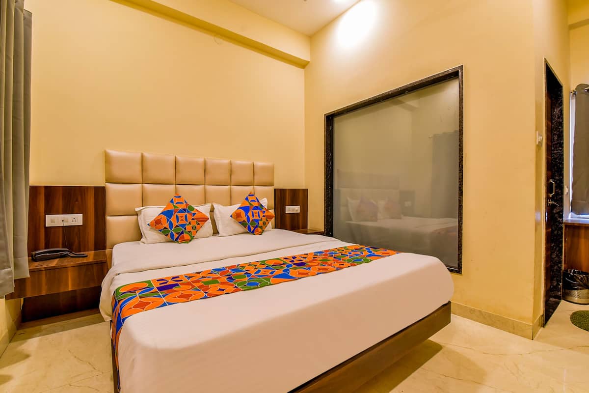 A hotel room with a large bed, a headboard, a nightstand, and a mirror on the wall.