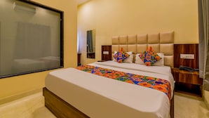 Una habitación de hotel con una cama grande, una mesita de noche, una ventana con vistas y un aire acondicionado de pared.