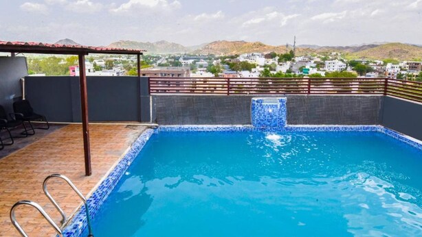 Una piscina en la azotea con vistas a un pueblo y montañas al fondo.