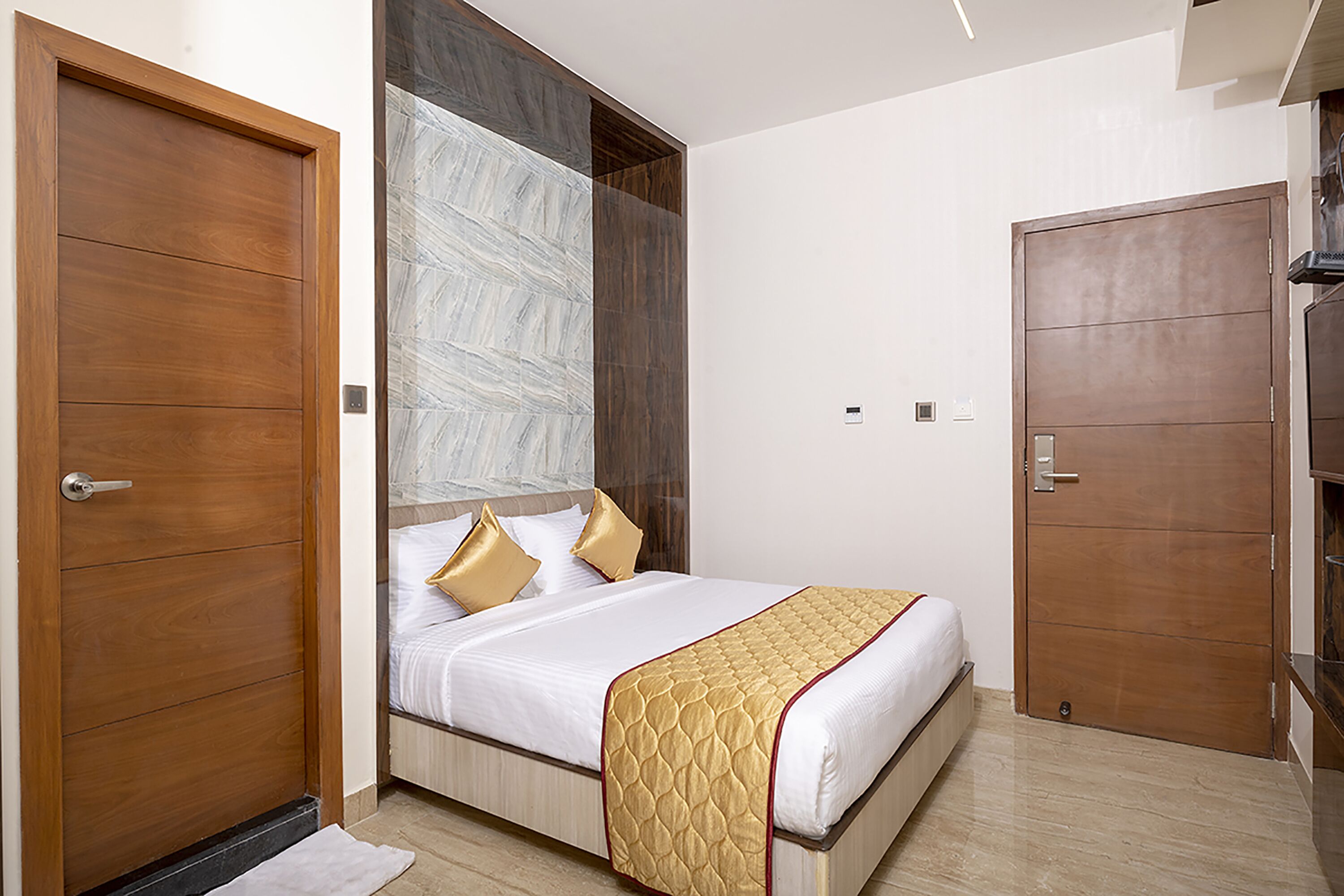A bedroom with a bed, wooden doors, and a large window.