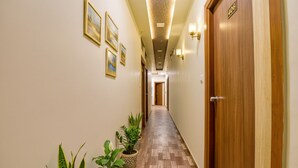 Un pasillo con suelo de madera, plantas en macetas y cuadros en las paredes.