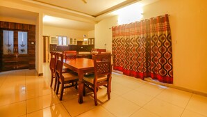 A dining area with a wooden table and chairs, a ceiling fan, and a kitchen in the background. - Via Direct Checkin - Hitech City (Hyderabad)