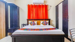 A bedroom with a bed, a window with red curtains, an air conditioning unit, and a wardrobe. - Via Direct Checkin - Hitech City (Hyderabad)