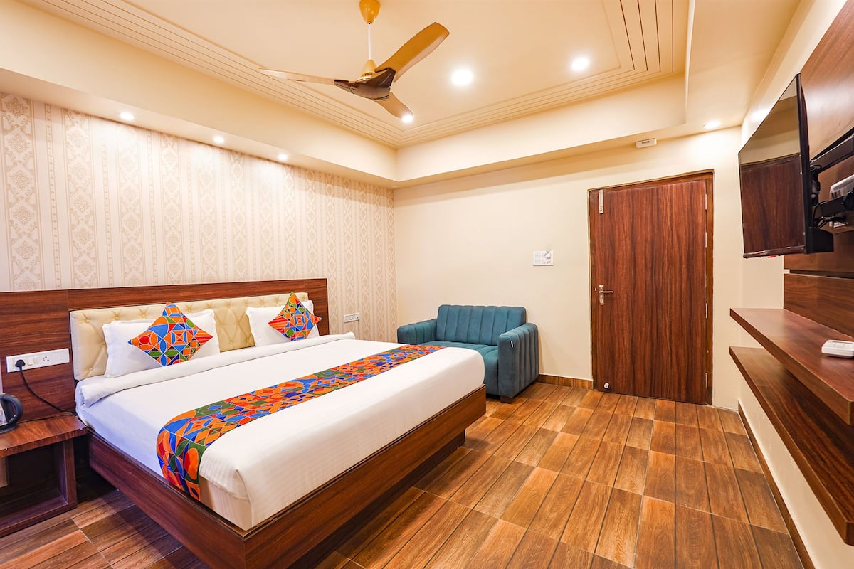 Habitación de hotel con una cama grande, un ventilador de techo, un armario de madera y un televisor sobre un mueble de madera.
