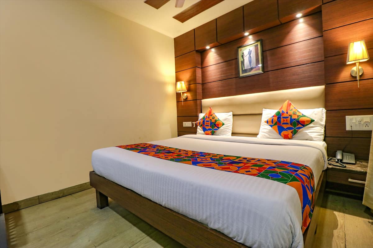 A hotel room with a large bed, wooden headboard, bedside lamps, and a nightstand with a phone.
