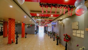 A hotel corridor with a polished marble floor, red pillars, and floral decorations. - FabHotel A One Noida Sector 11 (Noida)