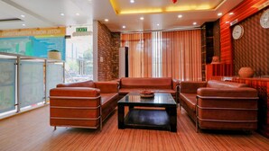 A modern lobby with leather sofas, a glass coffee table, and a brick accent wall. - FabHotel A One Noida Sector 11 (Noida)