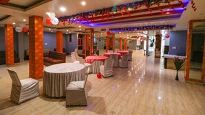 A spacious banquet hall with round tables and chairs, red and white balloons, and festive decorations. - FabHotel A One Noida Sector 11 (Noida)