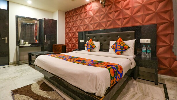 A modern hotel room with a large bed, a desk, and a mirror. - FabHotel A One Noida Sector 11 (Noida)