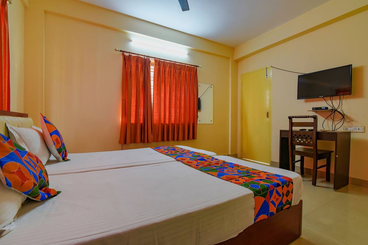 A hotel room with two beds, a television, a desk, and a chair.