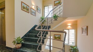 A staircase with metal railings, potted plants, and framed pictures on the walls. - Fabhotel Capital Casa (Barasat)