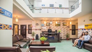 A hotel lobby with a reception desk, seating area, and a staircase. - Fabhotel Anutham (New Delhi)