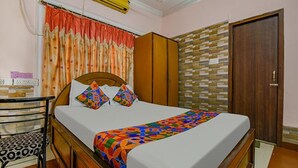Un dormitorio con cama, armario, escritorio y silla, y una puerta.