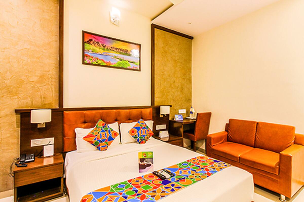 Habitación de hotel con una cama grande, un edredón de colores, un sofá, un escritorio y un cuadro en la pared.