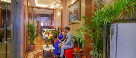 A lobby with a reception desk, a red sofa, and potted plants.
