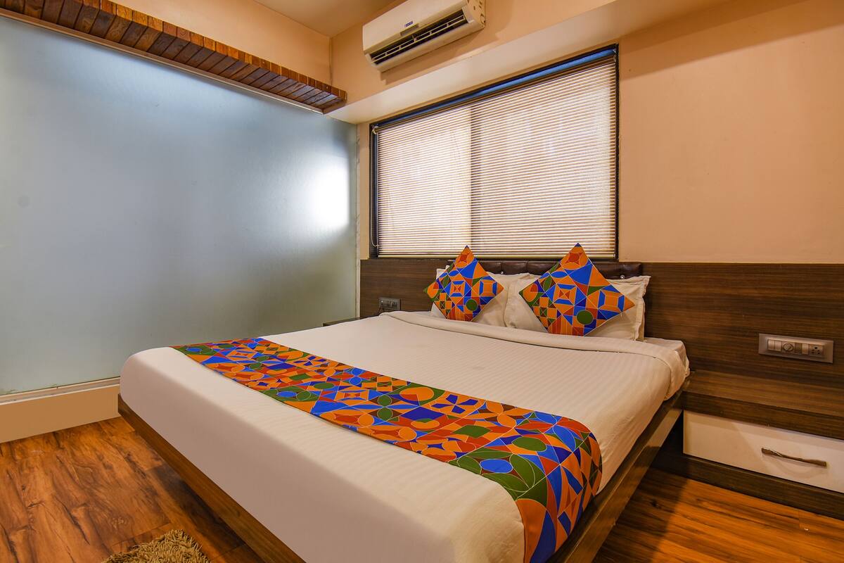 Un dormitorio con cama, ventana con persianas, cabecero de madera y aire acondicionado de pared.