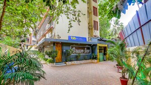 Hotel 'Dream Inn' con un letrero, rodeado de plantas en macetas y un camino empedrado.