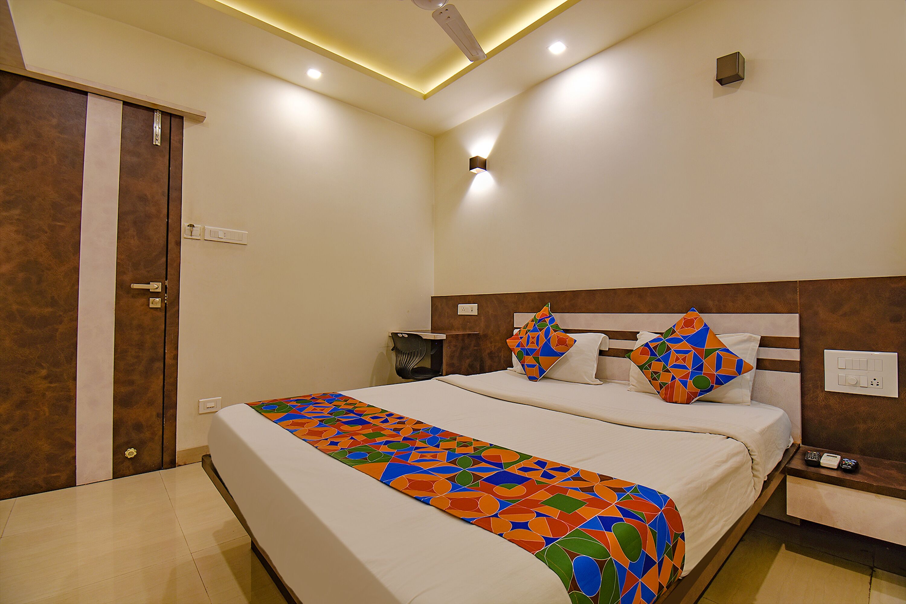 A hotel room with a large bed, a nightstand, a bedside table, and a wardrobe.