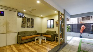 A reception area with a wooden floor, two sofas, a coffee table, a television, and a ceiling fan. - FabHotel Royce Studio (Pune)