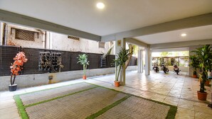 A spacious indoor area with tiled flooring, potted plants, and a wall with a decorative pattern. - FabHotel Royce Studio (Pune)