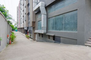 A narrow alleyway between buildings with potted plants and a fire hydrant. - FabHotel Alpha Center (Paud)