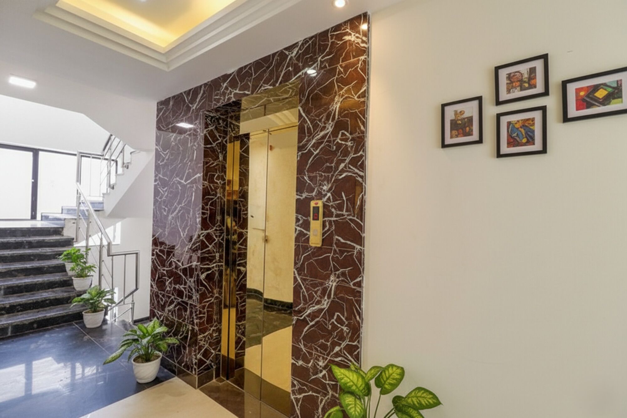A modern interior with a marble wall, a staircase, and framed artwork.