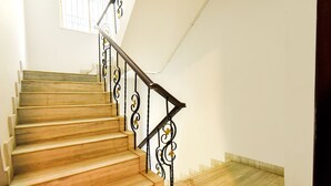 A wooden staircase with black metal railings and a white wall. - Fabhotel Eden (Baruipur)