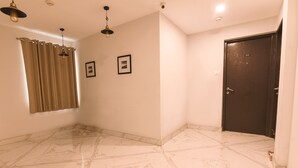 A room with a dark door, a framed picture, and a light fixture. - Fabhotel Eden (Baruipur)