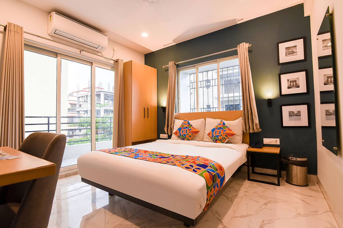 A hotel room with a large bed, a desk, and a view of the outside.