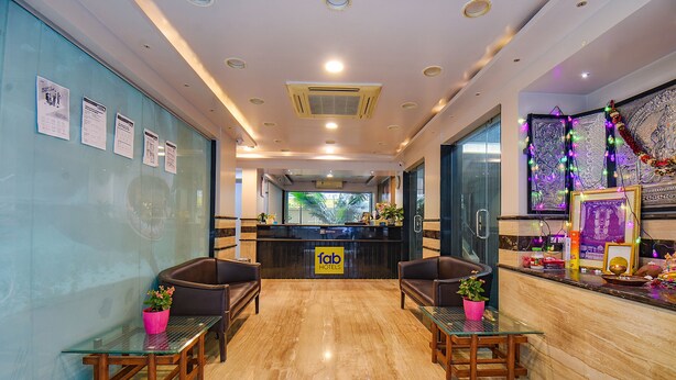 A hotel reception area with a marble floor, two reception desks, and seating arrangements. - Fabhotel Sr Wakad (Paud)